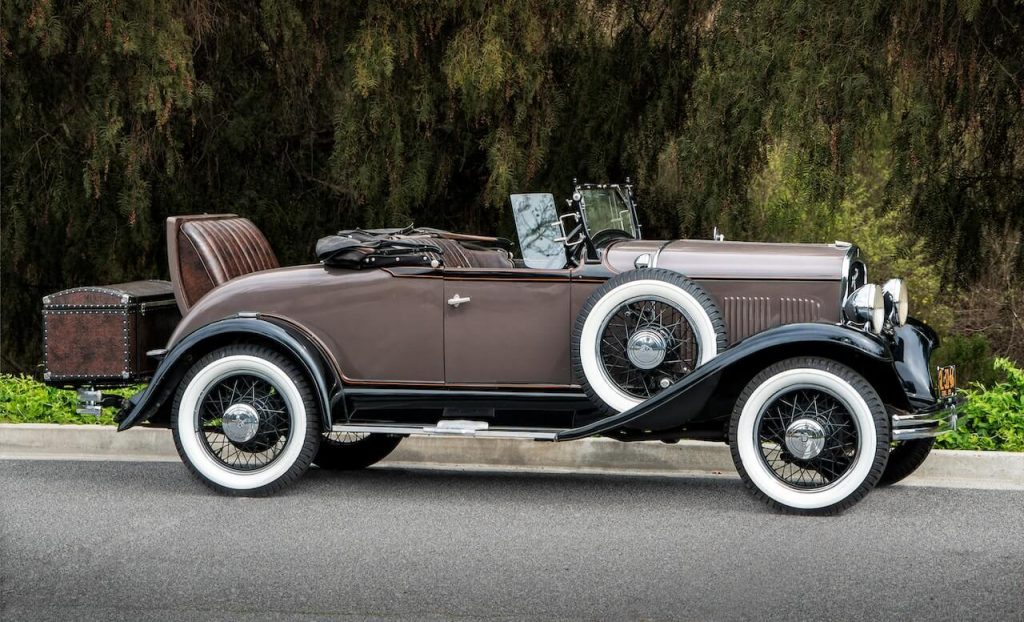 A vintage car exudes charm with a chest serving as its unique trunk.